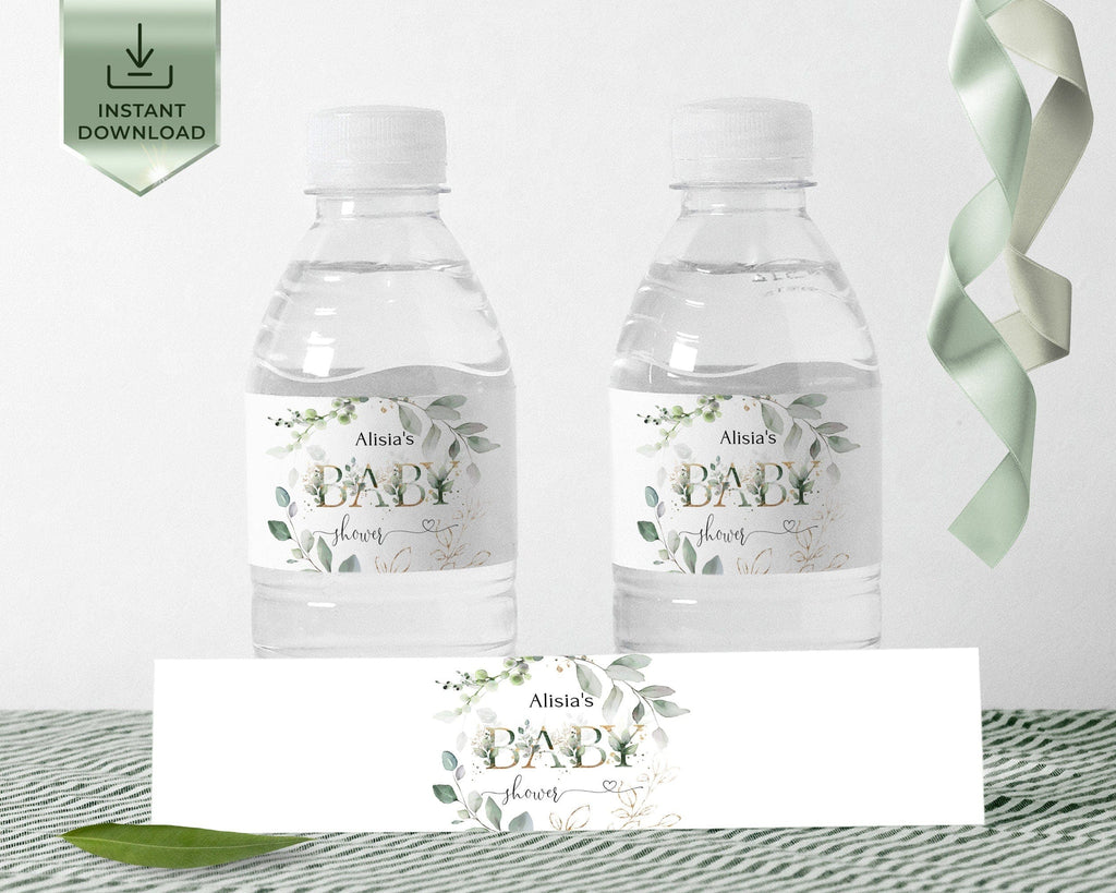 A pair of water bottles with greenery and gold eucalyptus baby shower bottle labels attached to them, displayed on a white surface with a ribbon in the background.
