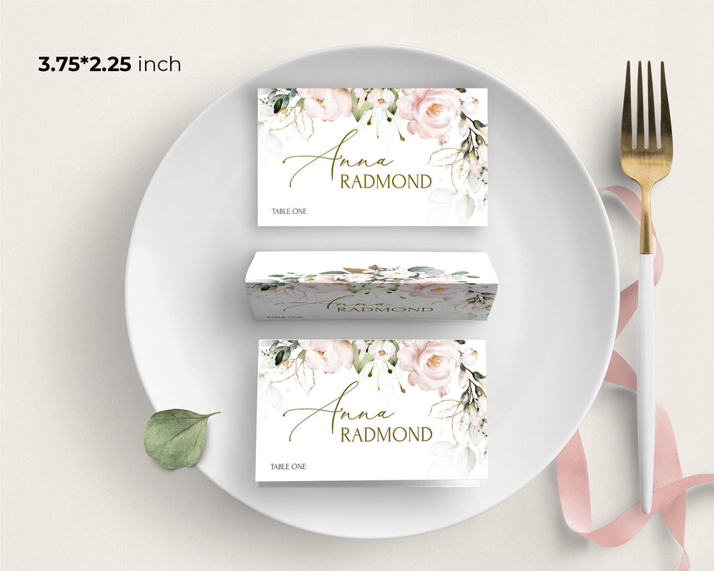 Place cards with floral design and text on a white plate with a gold fork.