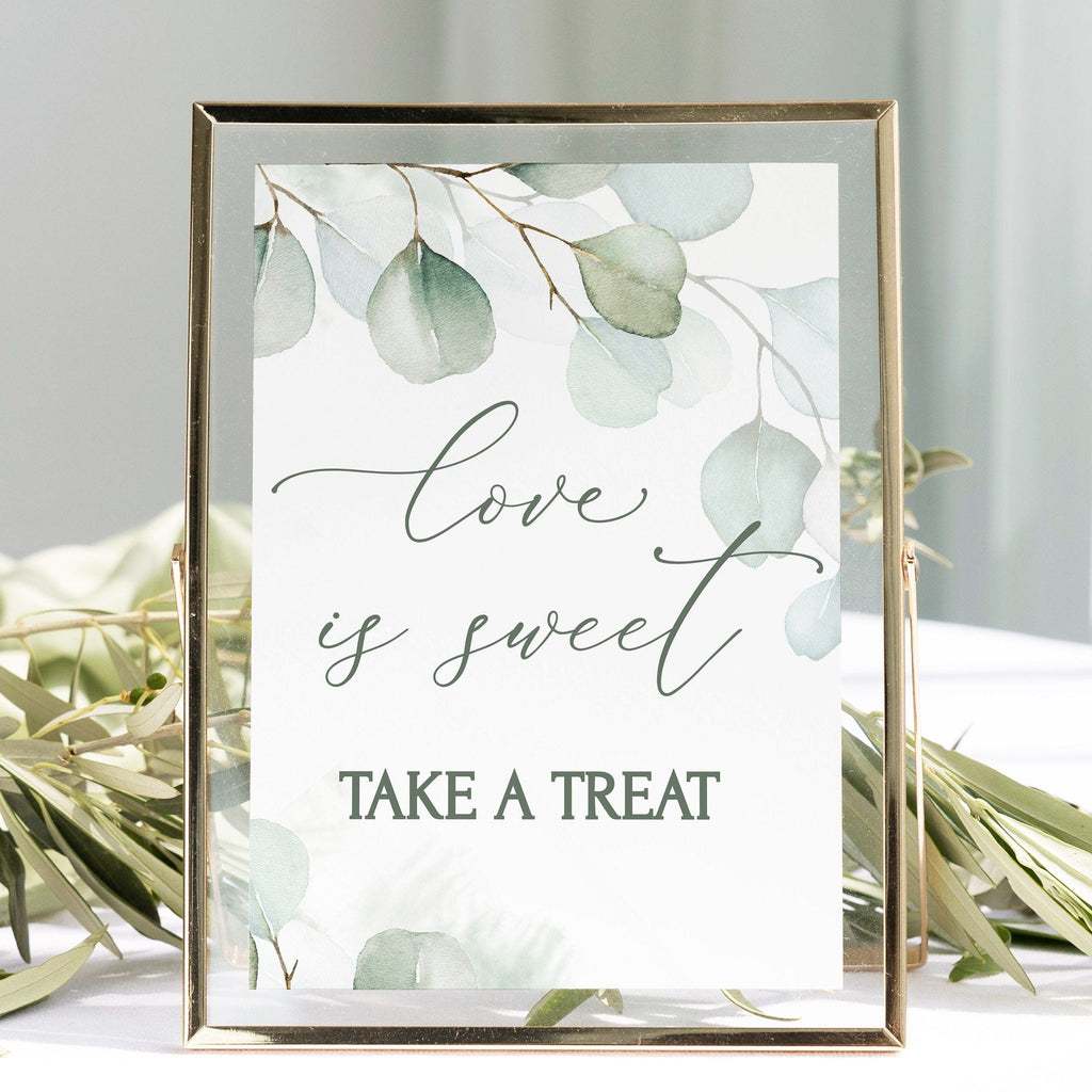 A digital dessert bar sign with the text 'love is sweet TAKE A TREAT' in a cursive and playful font, surrounded by a greenery border in a gold frame.