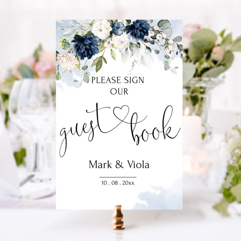 Wedding guest book sign with floral design and text 'Please sign our guest book Mark & Viola 10.08.20xx'.