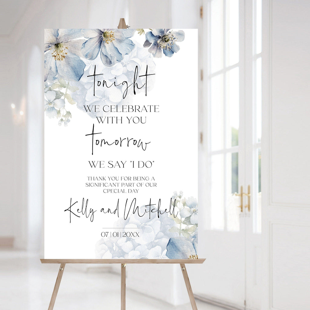 Wedding sign with floral design and text on an easel in a bright room.